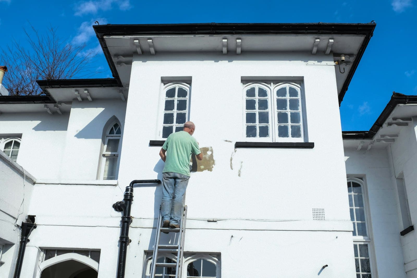 Pintor renovando la fachada de una casa en Elche
